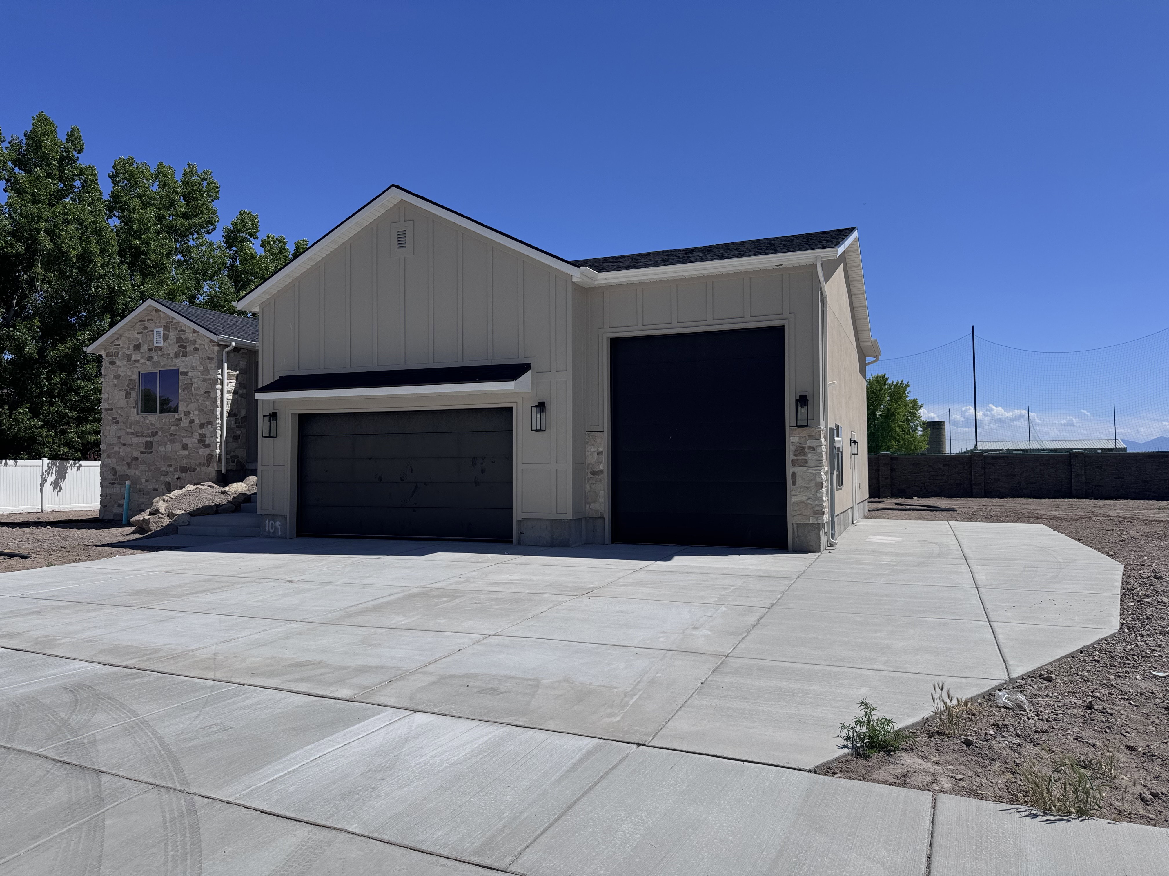 Two-story residence featuring light-colored vertical siding and stone veneer accents