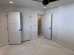 Interior room featuring white walls, three-panel interior doors with matte black hardware, recessed ceiling lighting, and a black ceiling fan