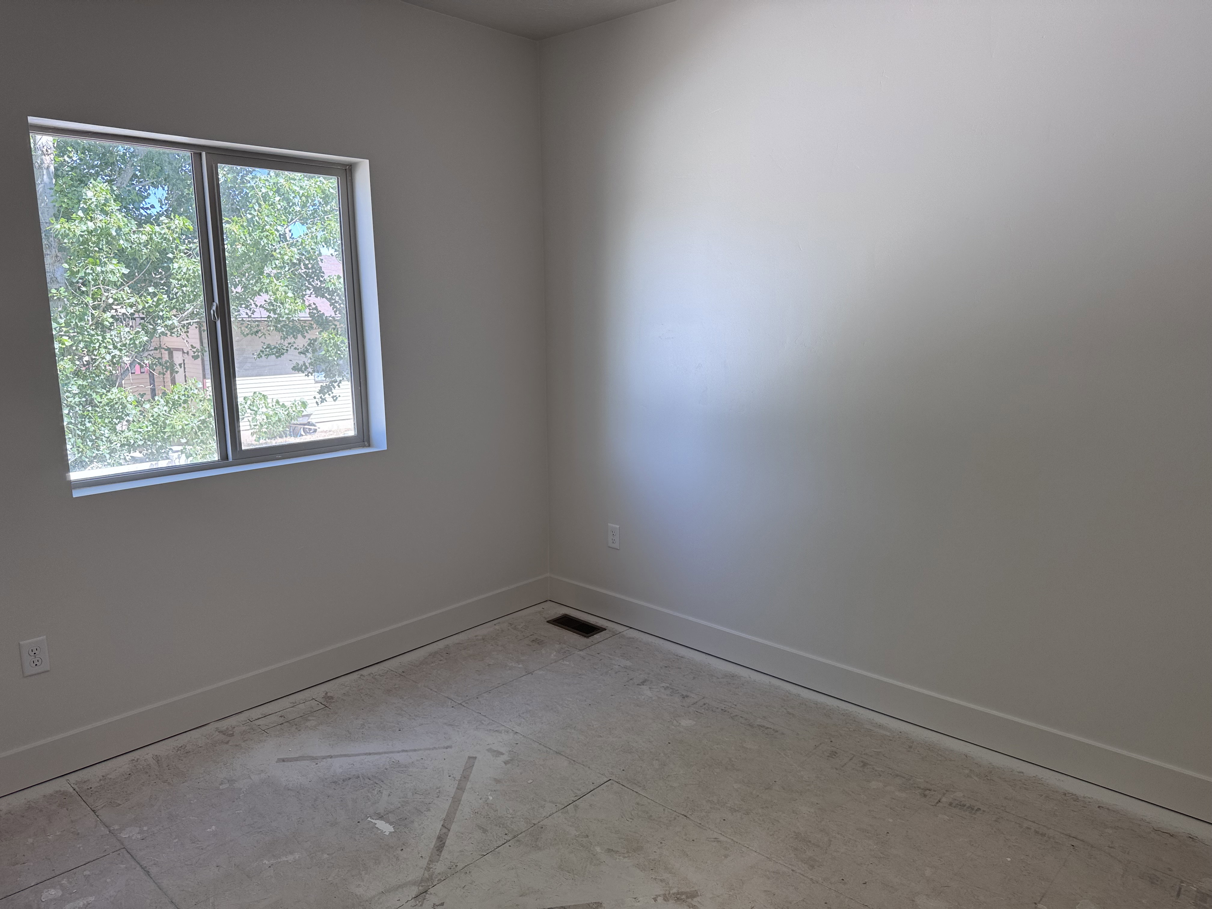 Bright interior space featuring a double-paned window, neutral wall paint, white trim, and a floor vent