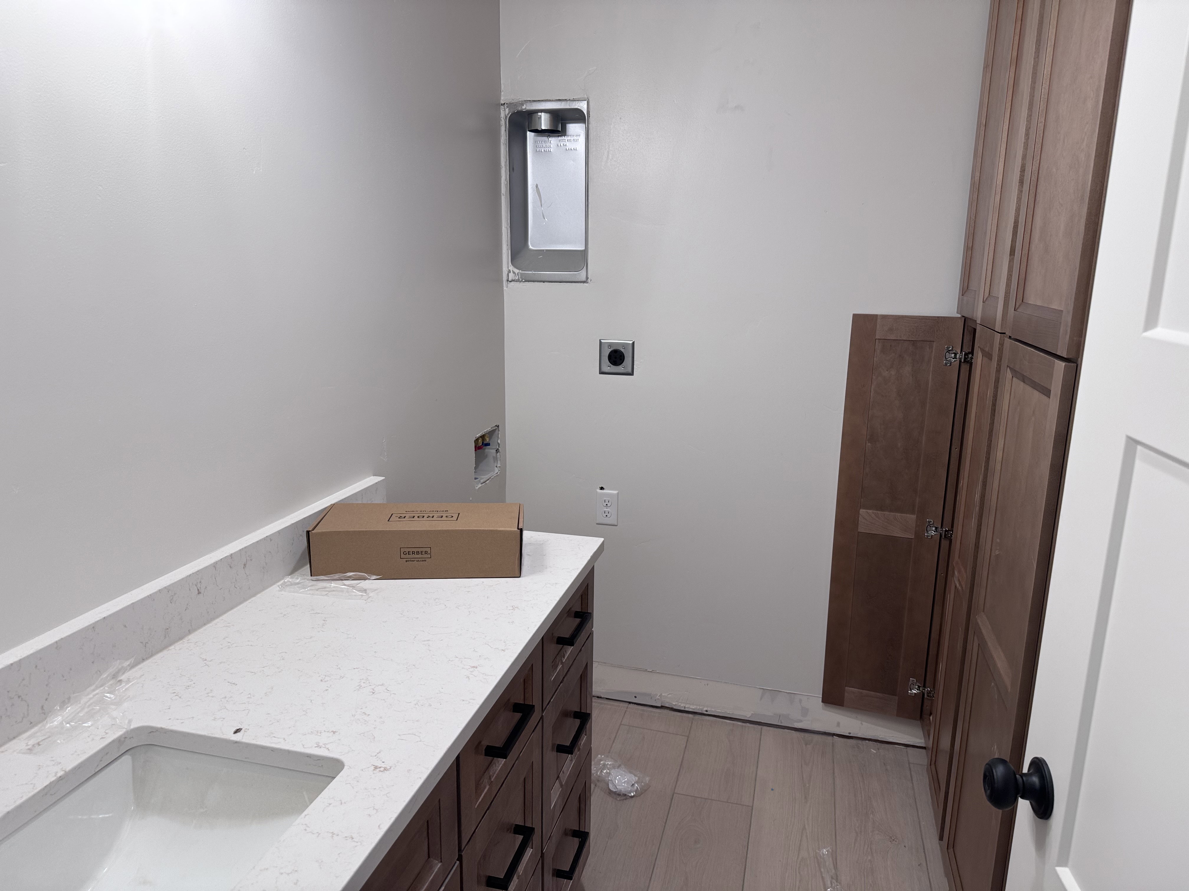 Utility space featuring a wood-finish flooring, built-in cabinetry, and a countertop with integrated sink