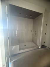 Spacious shower enclosure featuring a built-in bench, pebble-tile flooring, and multiple shower fixtures