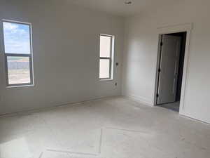 Spacious interior featuring a neutral color palette, two vertical windows, a recessed ceiling light, a paneled interior door, and clean baseboard trim