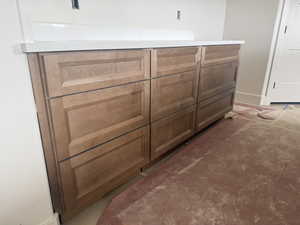 Wood-finish cabinetry with recessed panel doors, featuring a solid surface countertop and matching backsplash