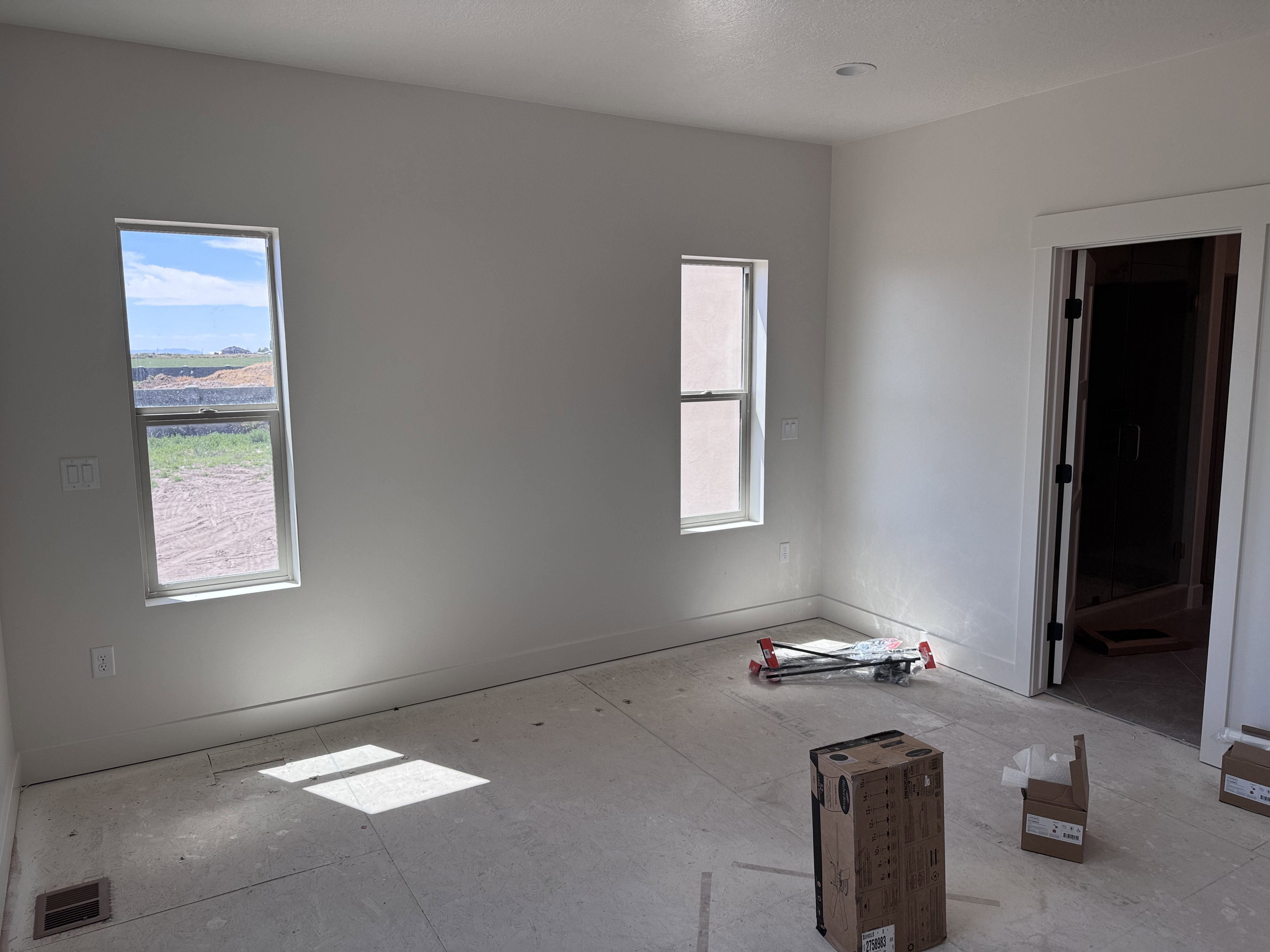 Bright interior room featuring a large doorway, two distinct windows, and recessed lighting
