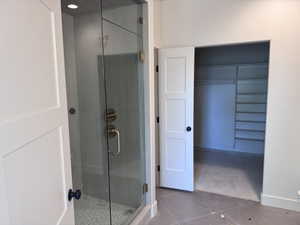Walk-in shower featuring a glass enclosure, brushed gold fixtures, and a pebble tile floor
