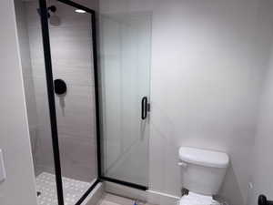 Shower enclosure with matte black framing, clear glass panel, and a matte black shower head and control