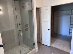 Walk-in shower with clear glass enclosure, brushed gold hardware, and pebble-finish floor