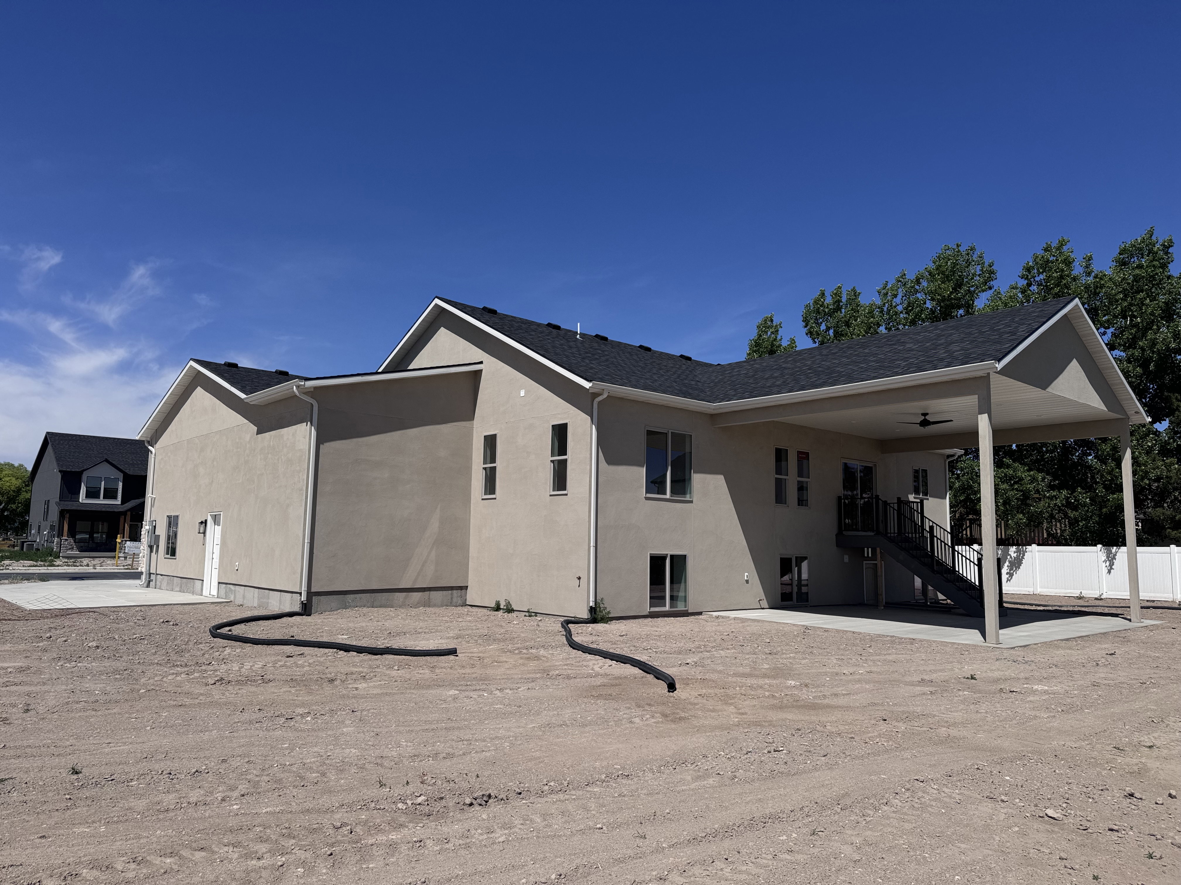 Contemporary stucco exterior with a covered patio featuring a ceiling fan