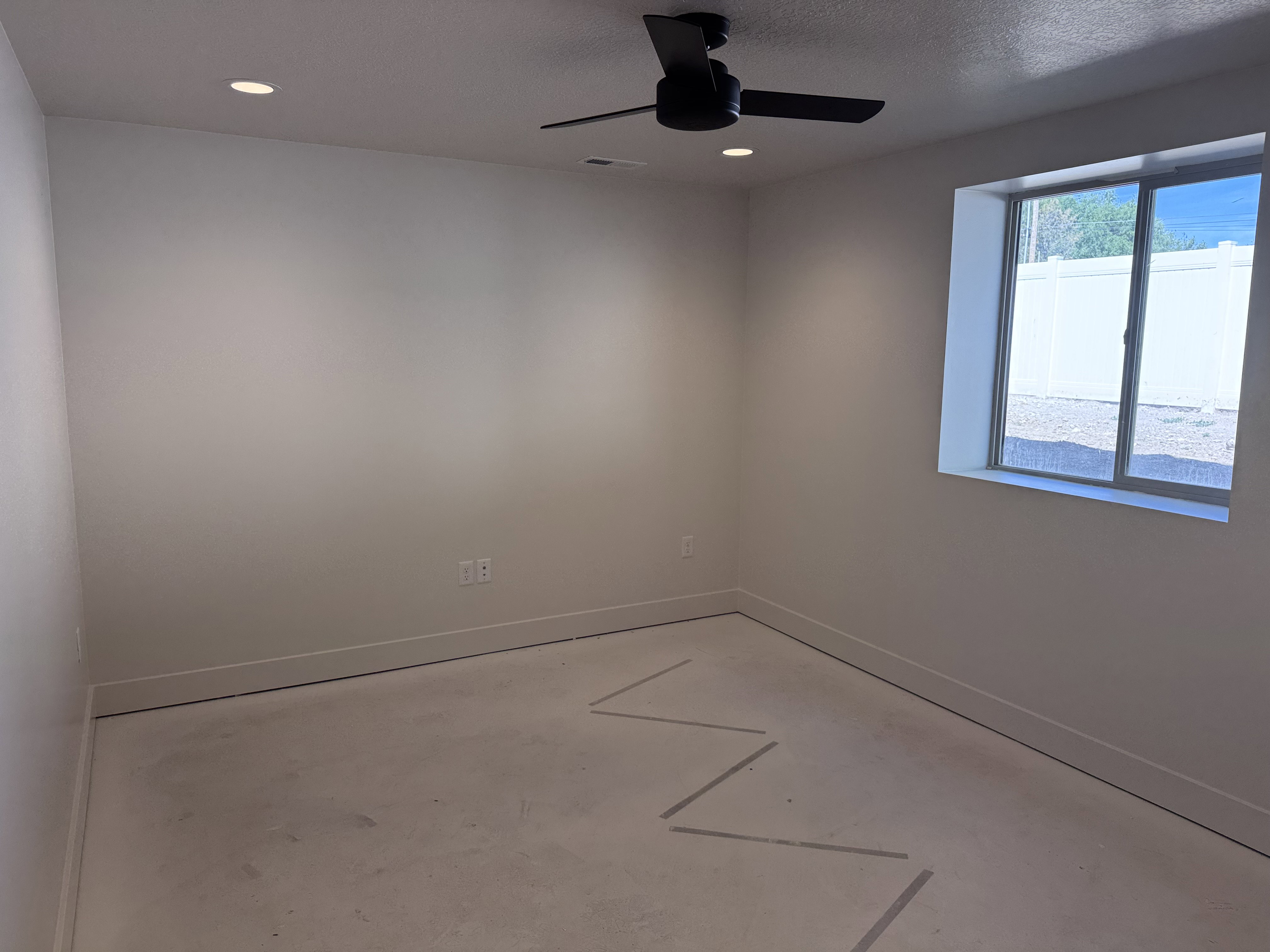 Room featuring a contemporary ceiling fan with matte black finish, recessed lighting, and a window providing natural illumination
