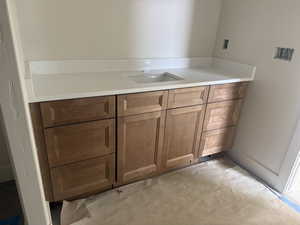 Cabinetry with a light wood finish, integrated rectangular sink, and a white countertop with a matching backsplash