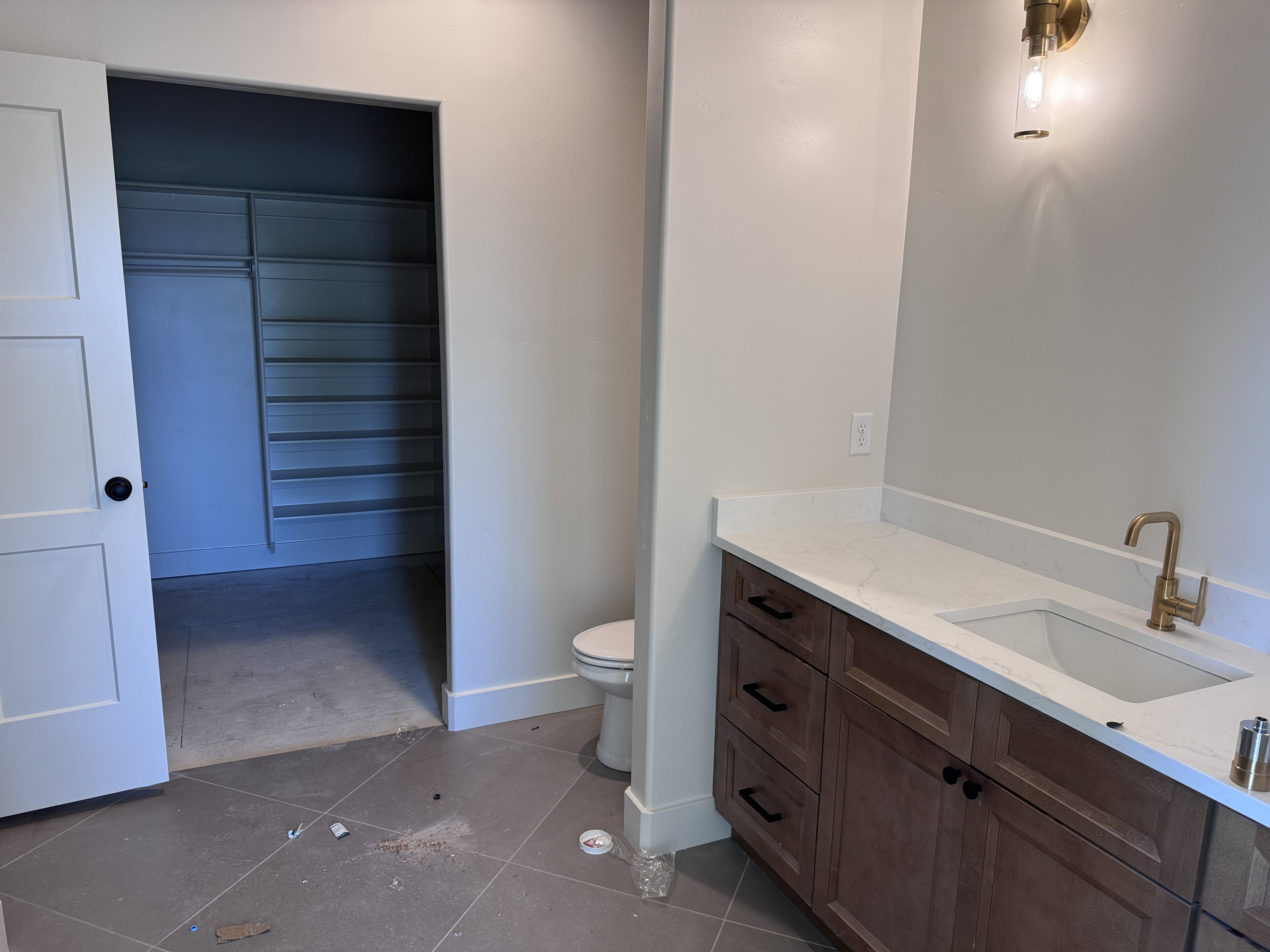 Bathroom vanity featuring wood-finish cabinetry, black hardware, an integrated rectangular sink, and a gold-finish faucet