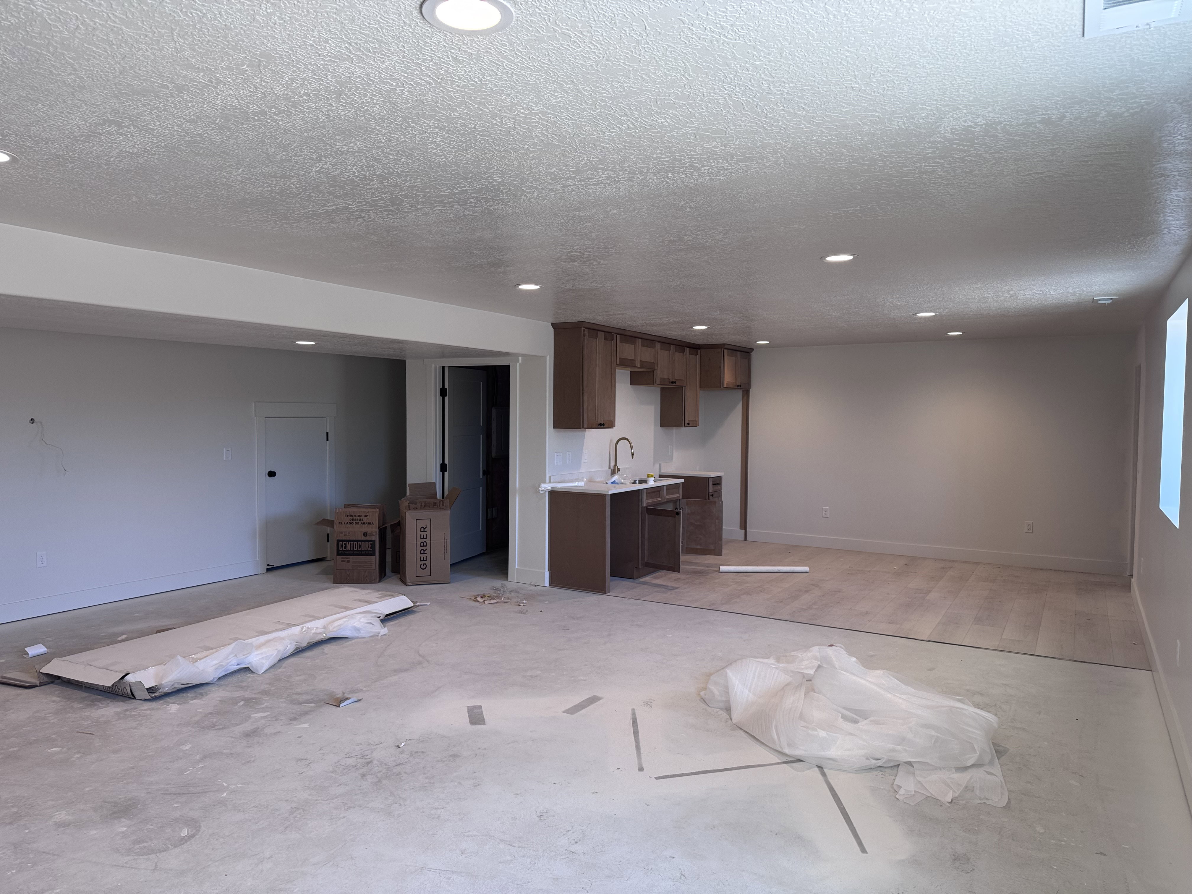 Recessed lighting illuminates an open concept space featuring a built-in wet bar with wood cabinetry and a stone-finish countertop