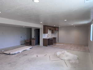 Recessed lighting illuminates an open concept space featuring a built-in wet bar with wood cabinetry and a stone-finish countertop