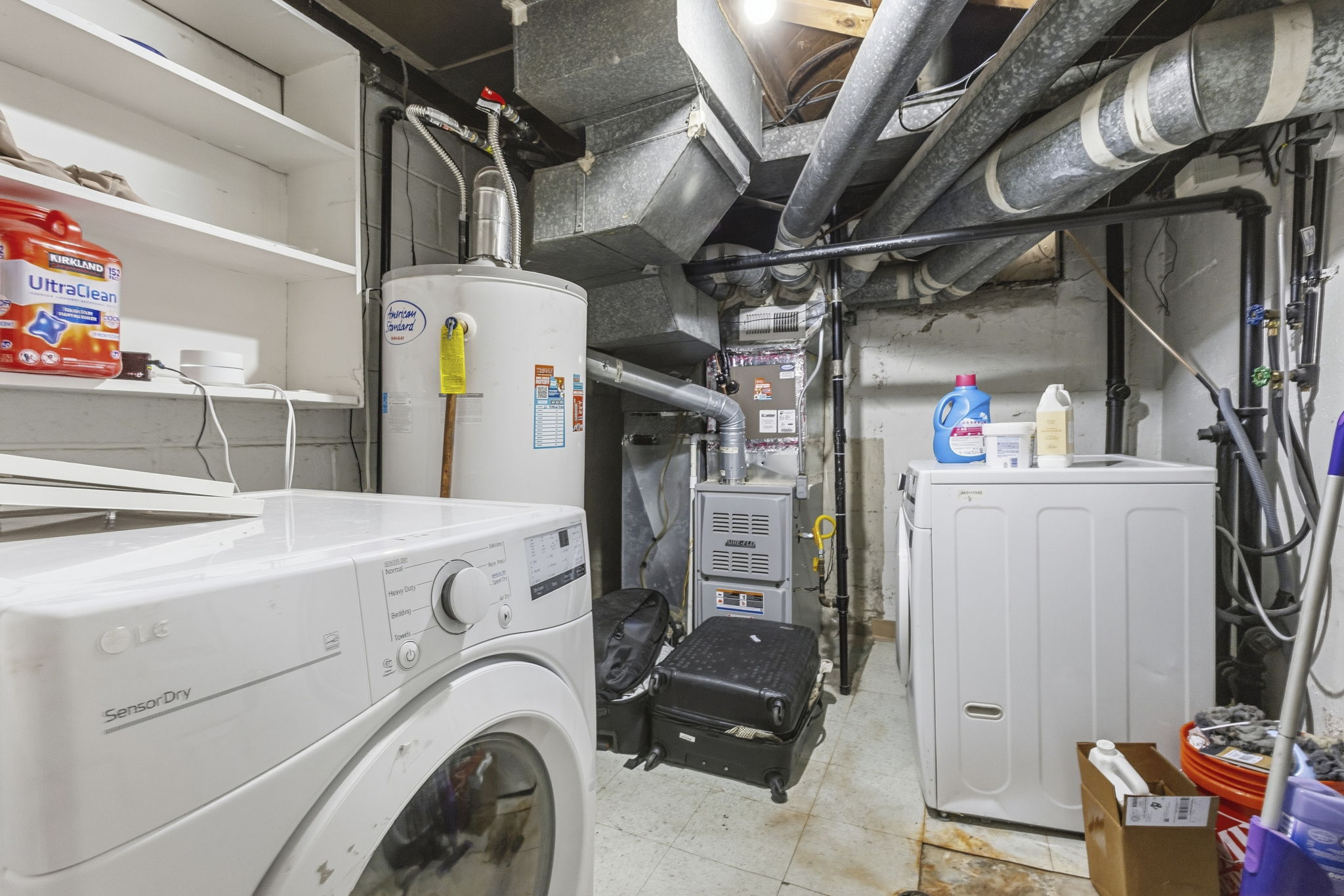 Dedicated utility space featuring laundry appliances, a water heater, furnace, and built-in shelving for storage