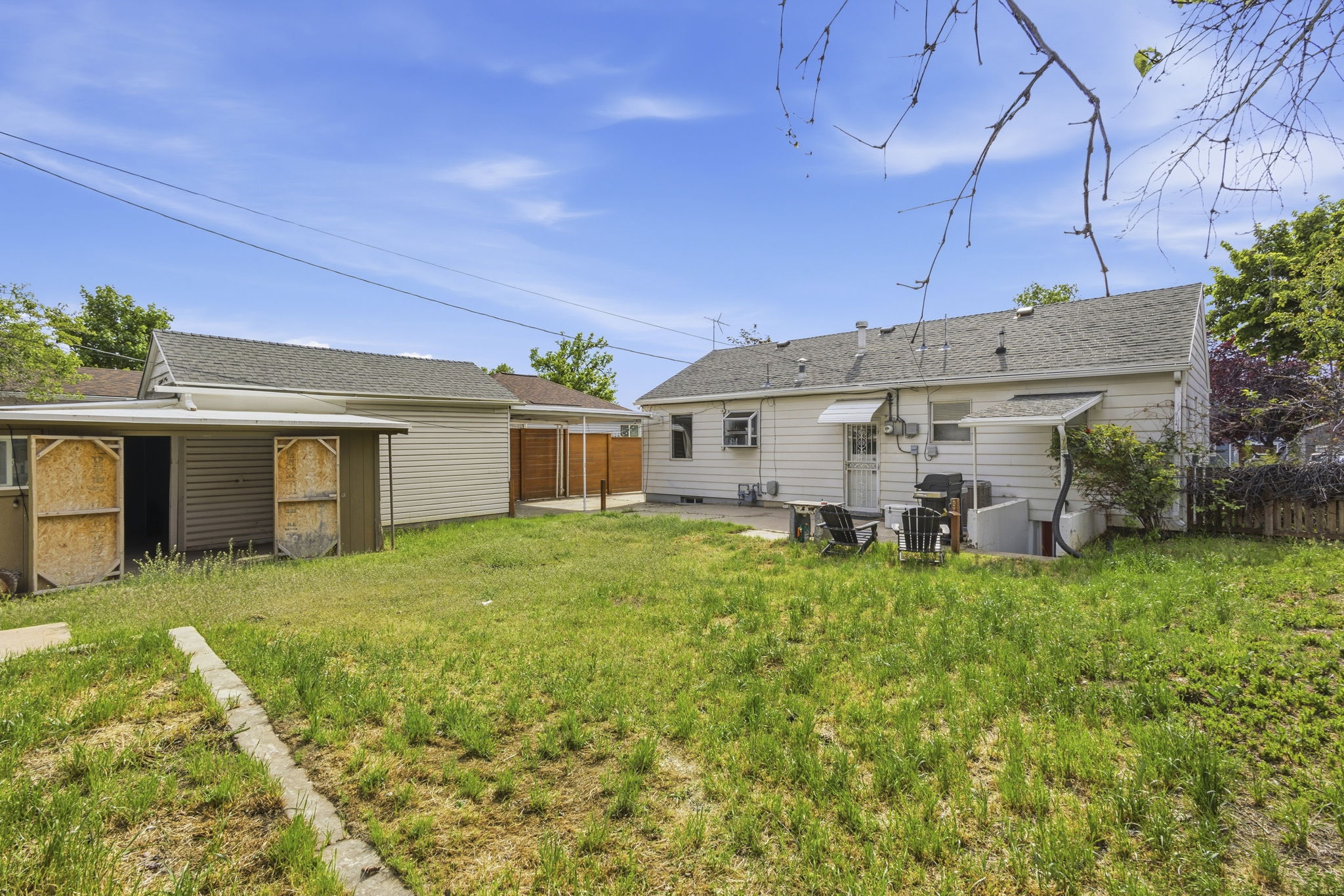 Expansive backyard featuring a concrete patio, a detached garage with a side storage shed, and a privacy fence