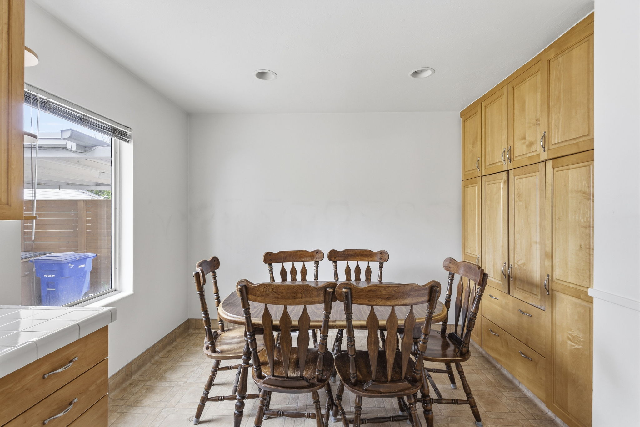 Built-in cabinetry providing extensive storage in a bright dining area featuring recessed lighting, tile flooring, and a window for natural light