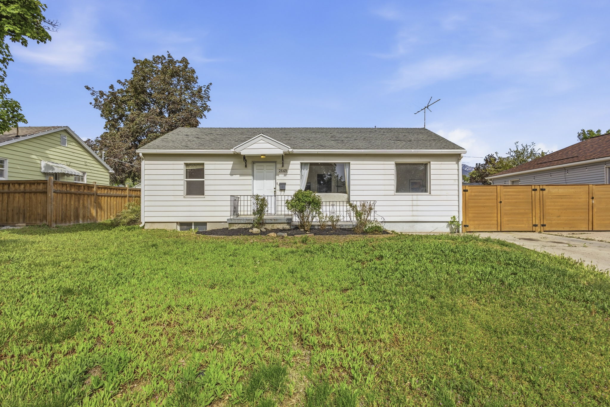 White siding exterior with a dark roof and a front porch featuring white railings