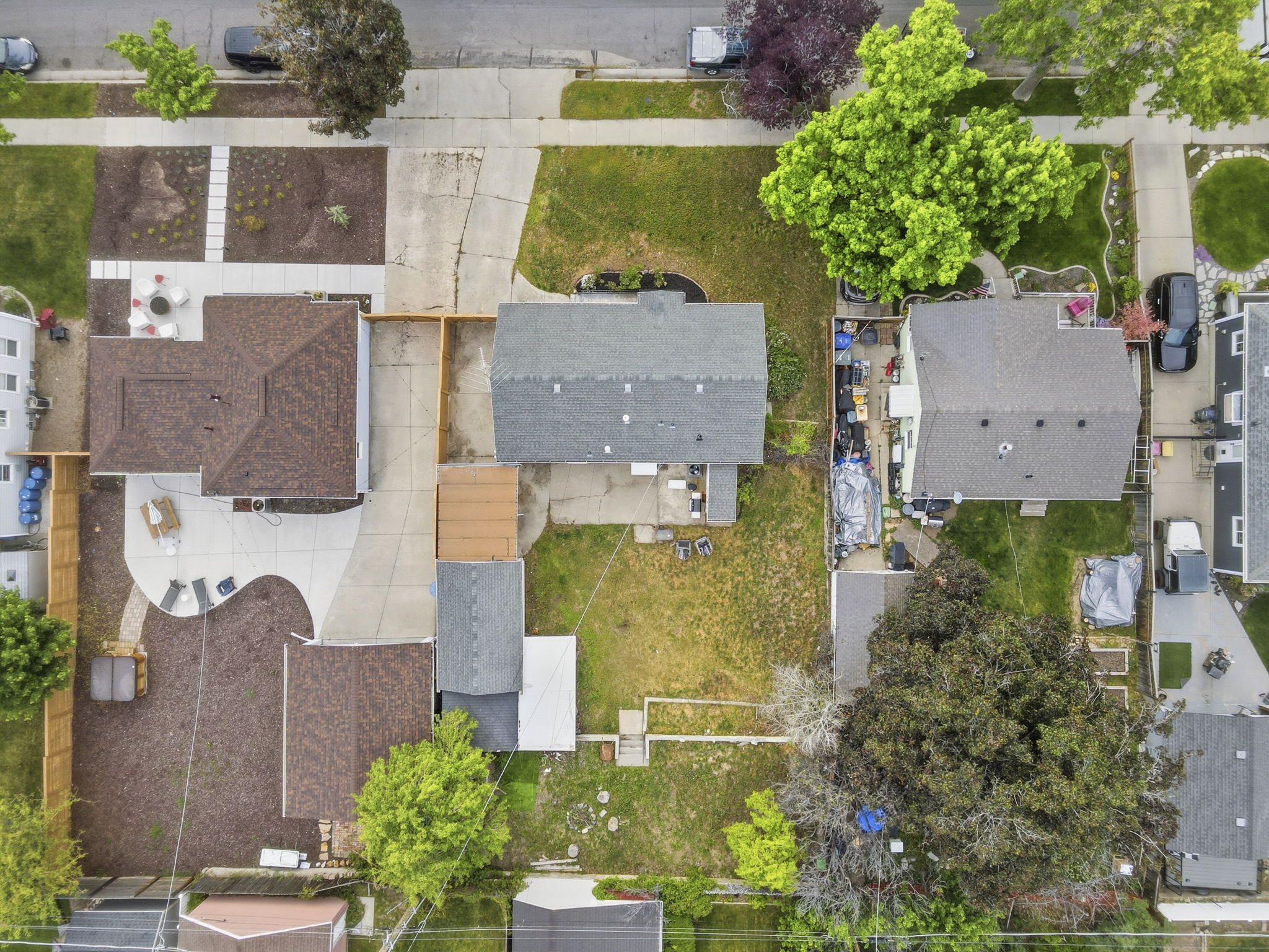 Expansive lot featuring two residential structures with shingle roofs, concrete driveways, and mature landscaping