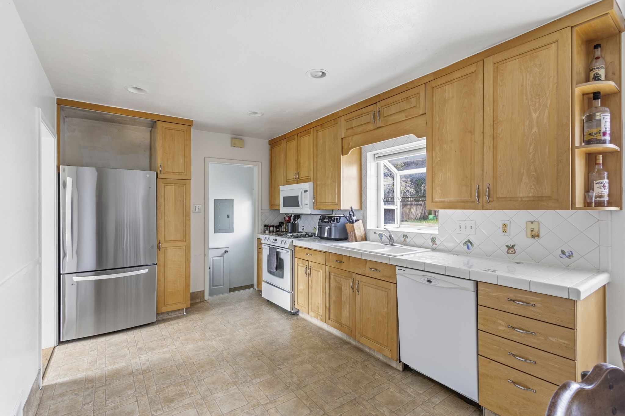 Kitchen featuring wood cabinetry, a tile countertop, and a white tile backsplash with decorative accents