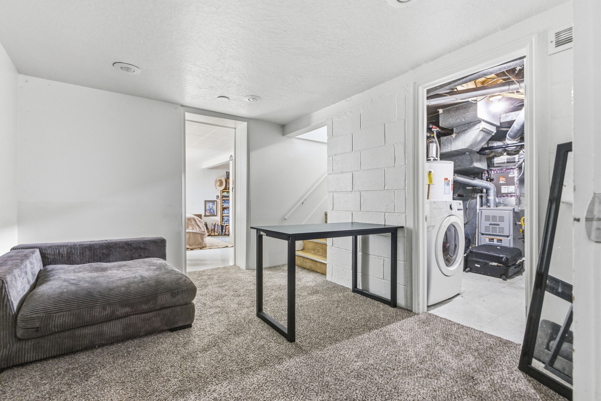 Carpeted interior space featuring white painted walls, recessed lighting, and a utility closet with a washer and water heater