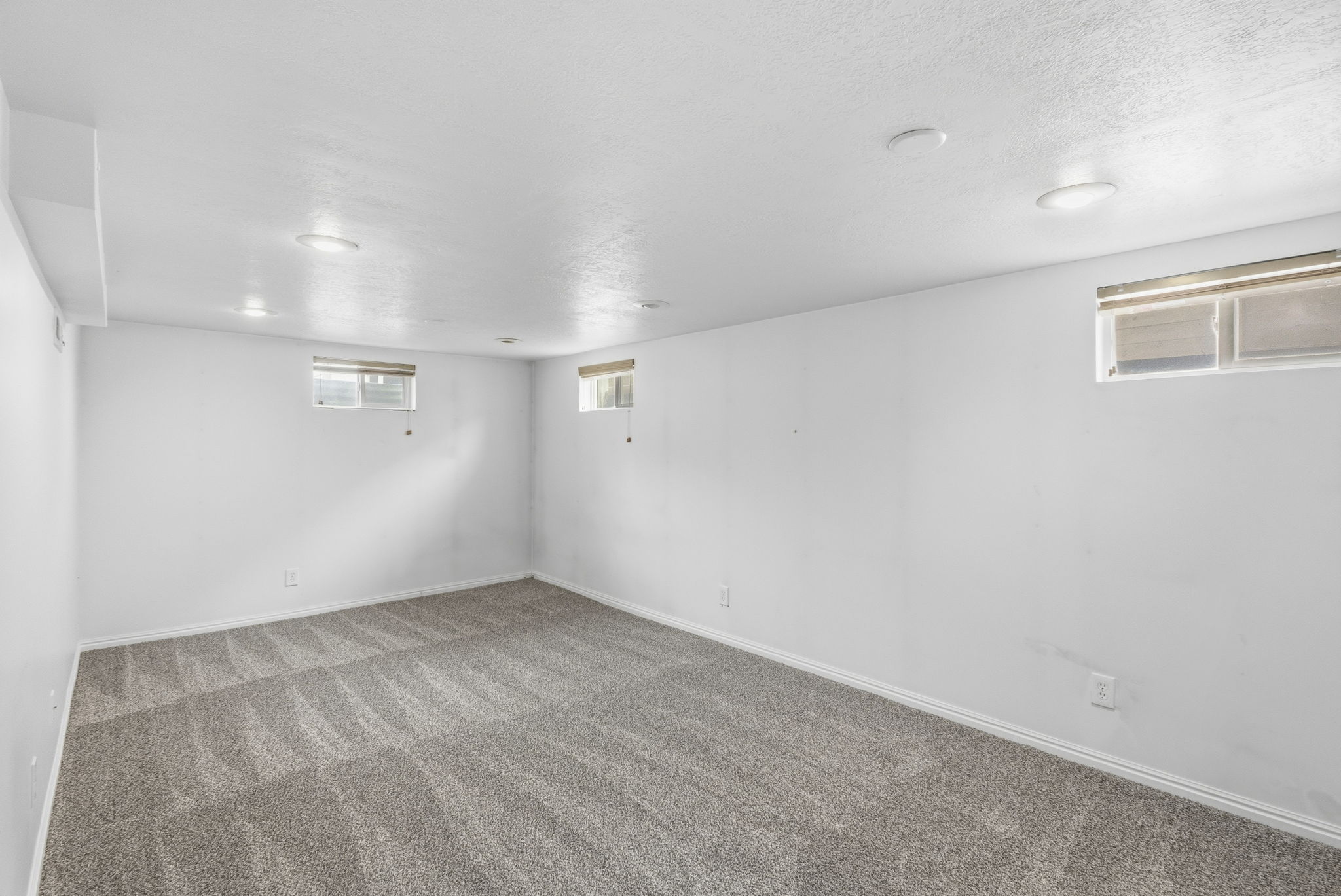Spacious room featuring new carpeting, multiple windows, and recessed lighting for ample illumination