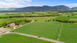 Expansive green fields surrounding a residential property with a winding driveway