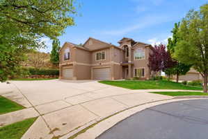 Stucco exterior residence with arched entry, multiple garages, and a concrete driveway