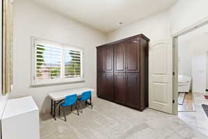 Room featuring light-toned carpeting and a large window with white plantation shutters
