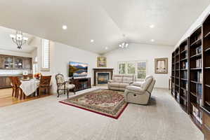 Vaulted ceilings accentuating the living area featuring a stone fireplace, built-in curved bookcases, and recessed lighting