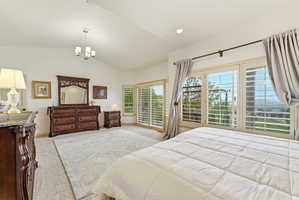 Spacious bedroom featuring vaulted ceilings, recessed lighting, and a contemporary chandelier