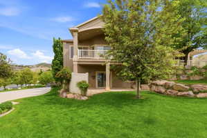 Expansive rear exterior featuring a manicured lawn, multi-level design, and a stone retaining wall