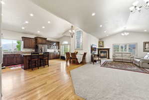 Vaulted ceilings accent an open-concept living area featuring wood-finish flooring in the kitchen and dining areas