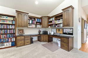 Dedicated office space featuring extensive built-in cabinetry, integrated desk areas, and a full-height bookshelf