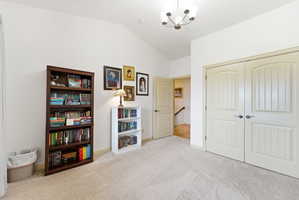 Vaulted ceiling with a central chandelier, light-toned carpeting, and double panel doors with brushed nickel hardware