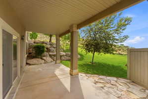 Covered patio featuring a concrete slab, flagstone detailing, and supporting columns
