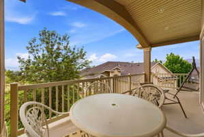Spacious covered balcony featuring a light-colored railing, arched support columns, and recessed lighting