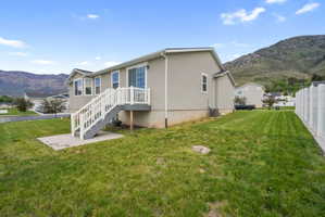 Rear exterior featuring a multi-pane sliding glass door, a bay window, and a white deck with stairs leading to a concrete patio