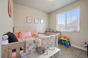 Well-lit room with a large window, neutral wall paint, and gray carpet flooring