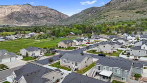 Residential community with mountain backdrop, featuring various home styles, manicured lawns, and paved streets