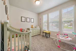 Carpeted room featuring three vertical windows with blinds, a light-colored dresser, and a ceiling-mounted light fixture