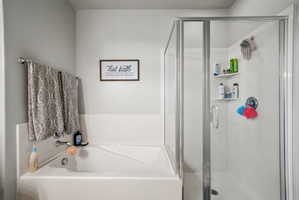 Bright bathroom featuring a built-in tub and a separate glass-enclosed shower with integrated shelving