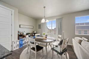 Open-concept dining area featuring wood-finish flooring, a contemporary chandelier, and a sliding glass door providing exterior access