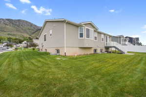 Expansive rear lawn featuring a white vinyl privacy fence, full-light walk-out basement windows, and a wood-deck staircase with white railings