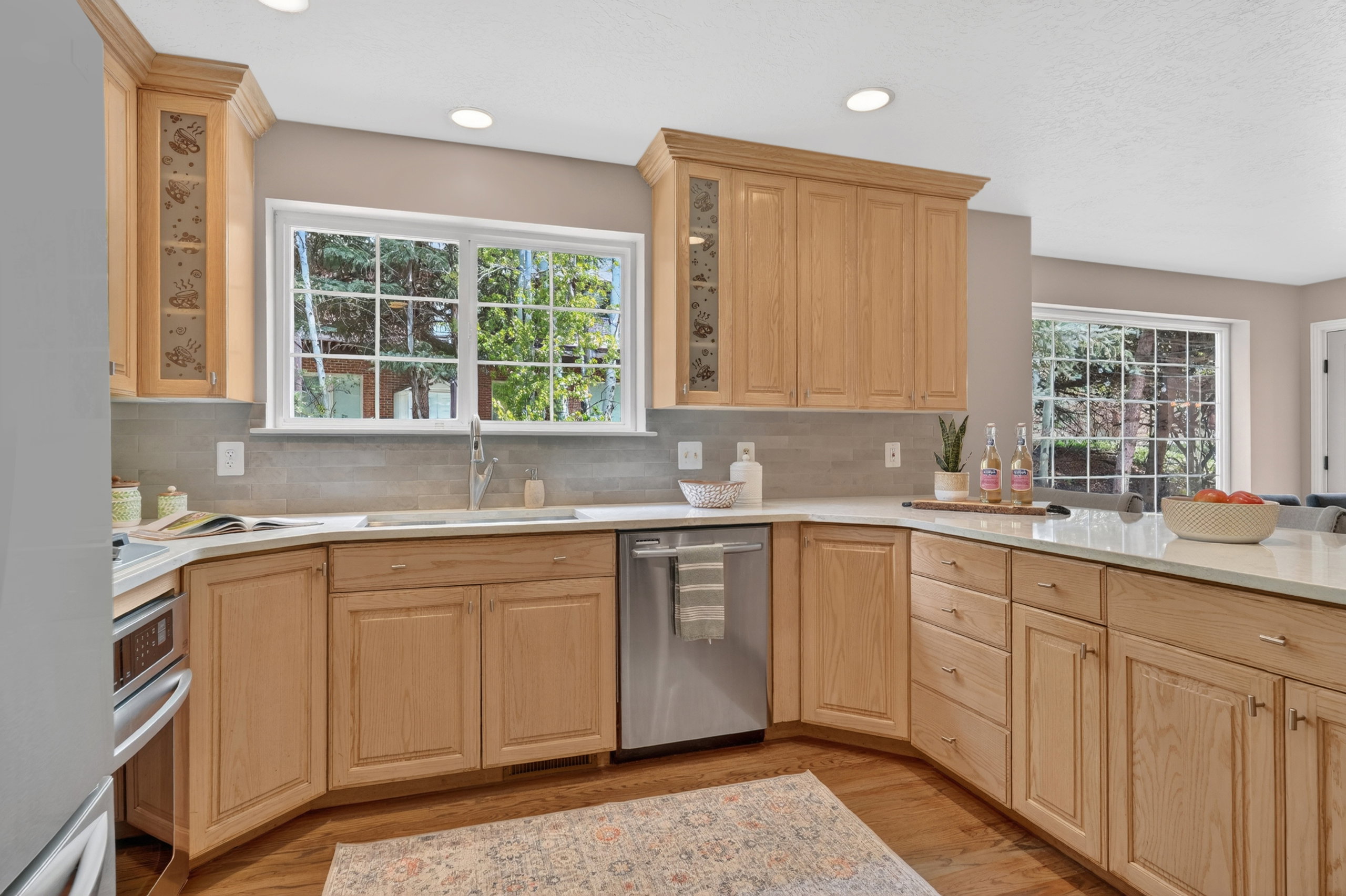 Kitchen featuring light wood cabinetry, light countertops, a stainless steel dishwasher, and a window above the sink