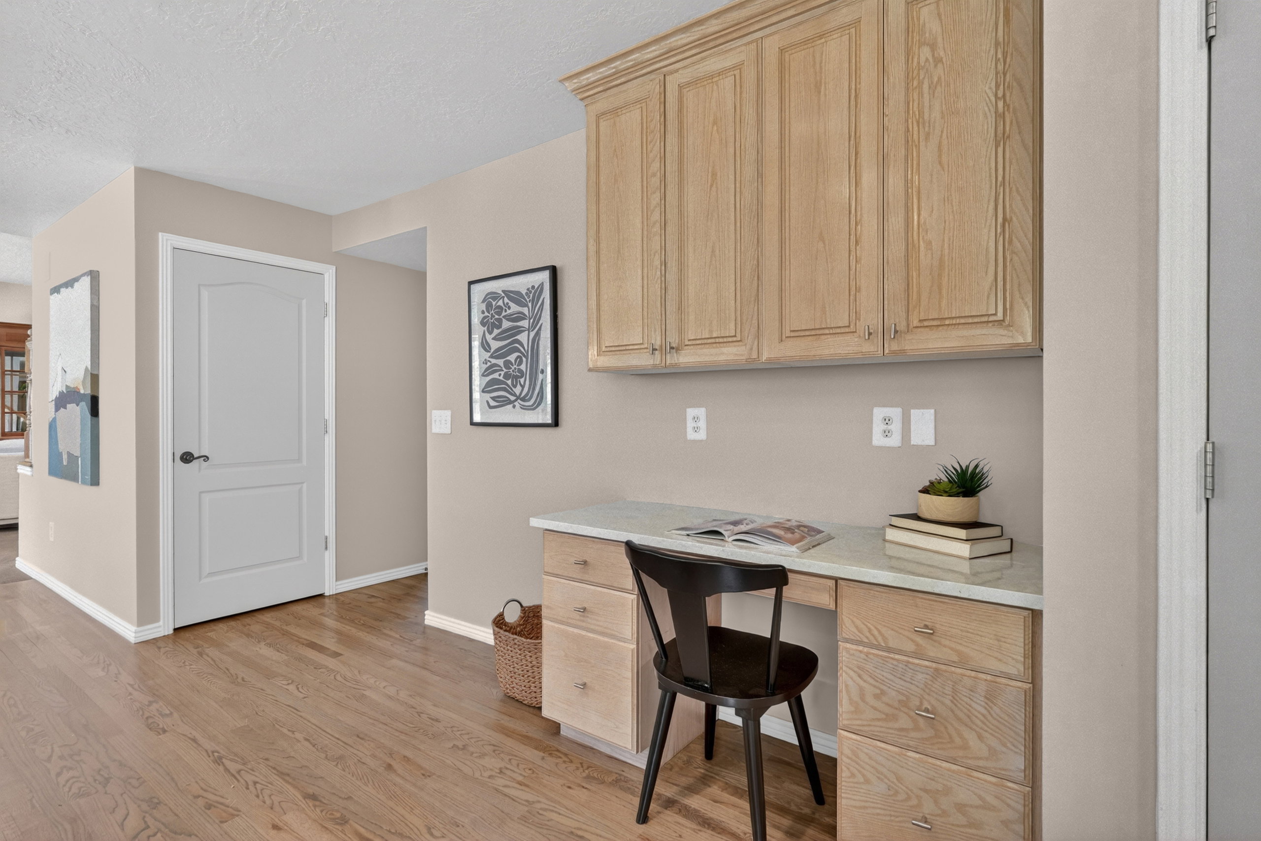 Integrated built-in desk with a light-toned countertop, accompanied by overhead wood-finish cabinetry