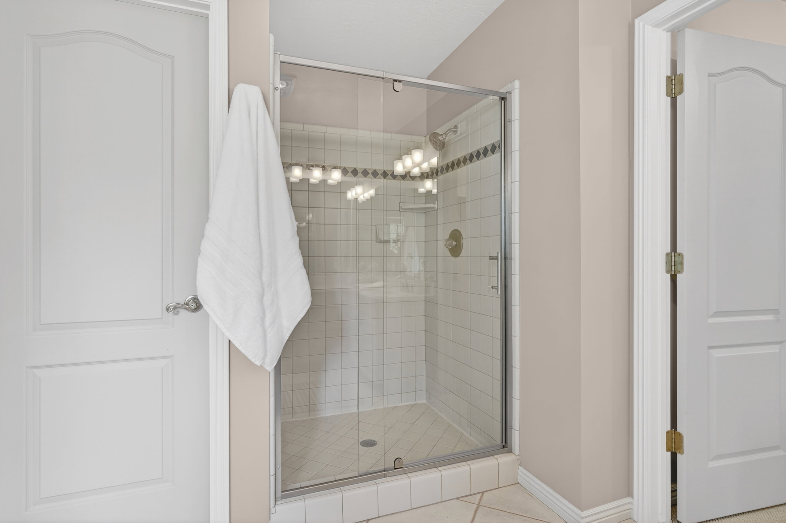 Glass-enclosed shower featuring white subway tile, decorative accent tile, and a gold-toned shower fixture