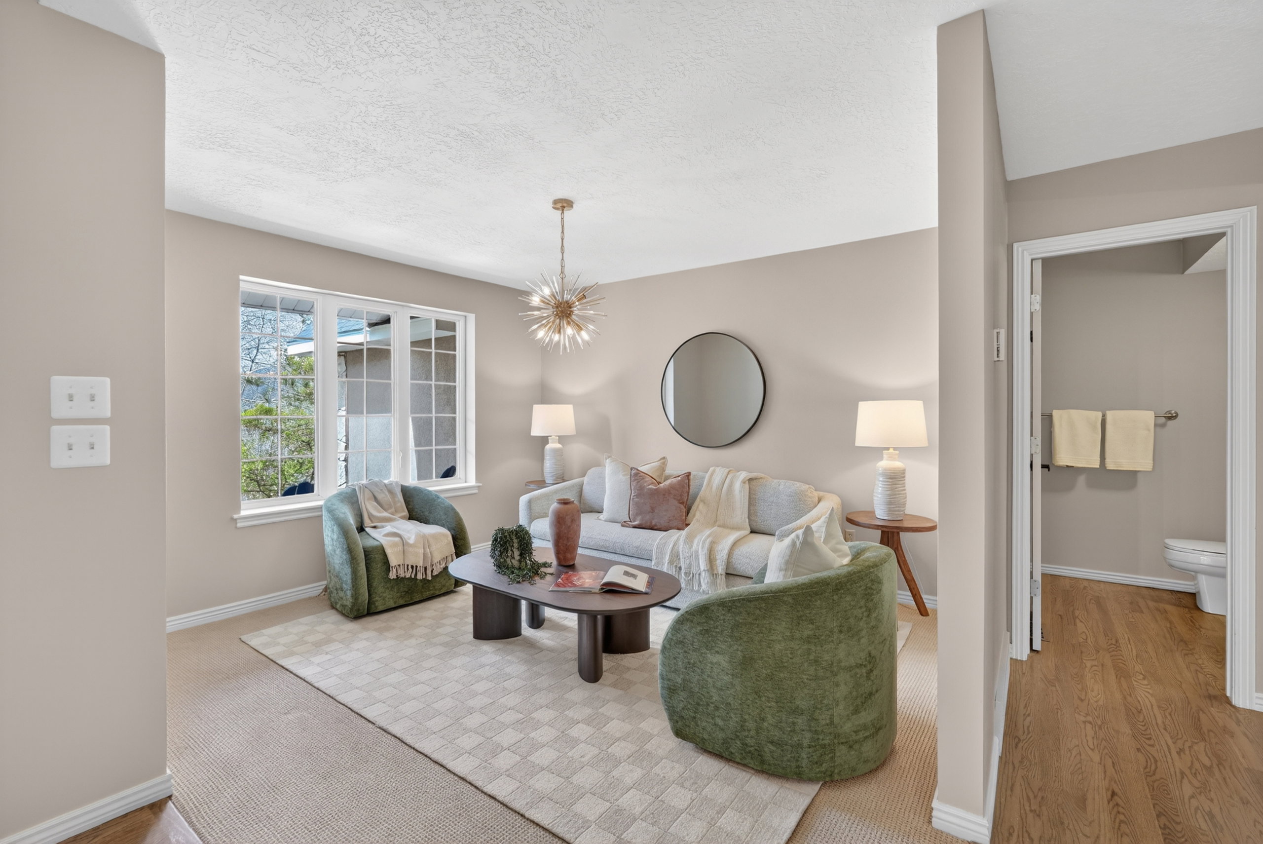 Carpeted living area featuring a large window, a modern chandelier, and light-toned walls