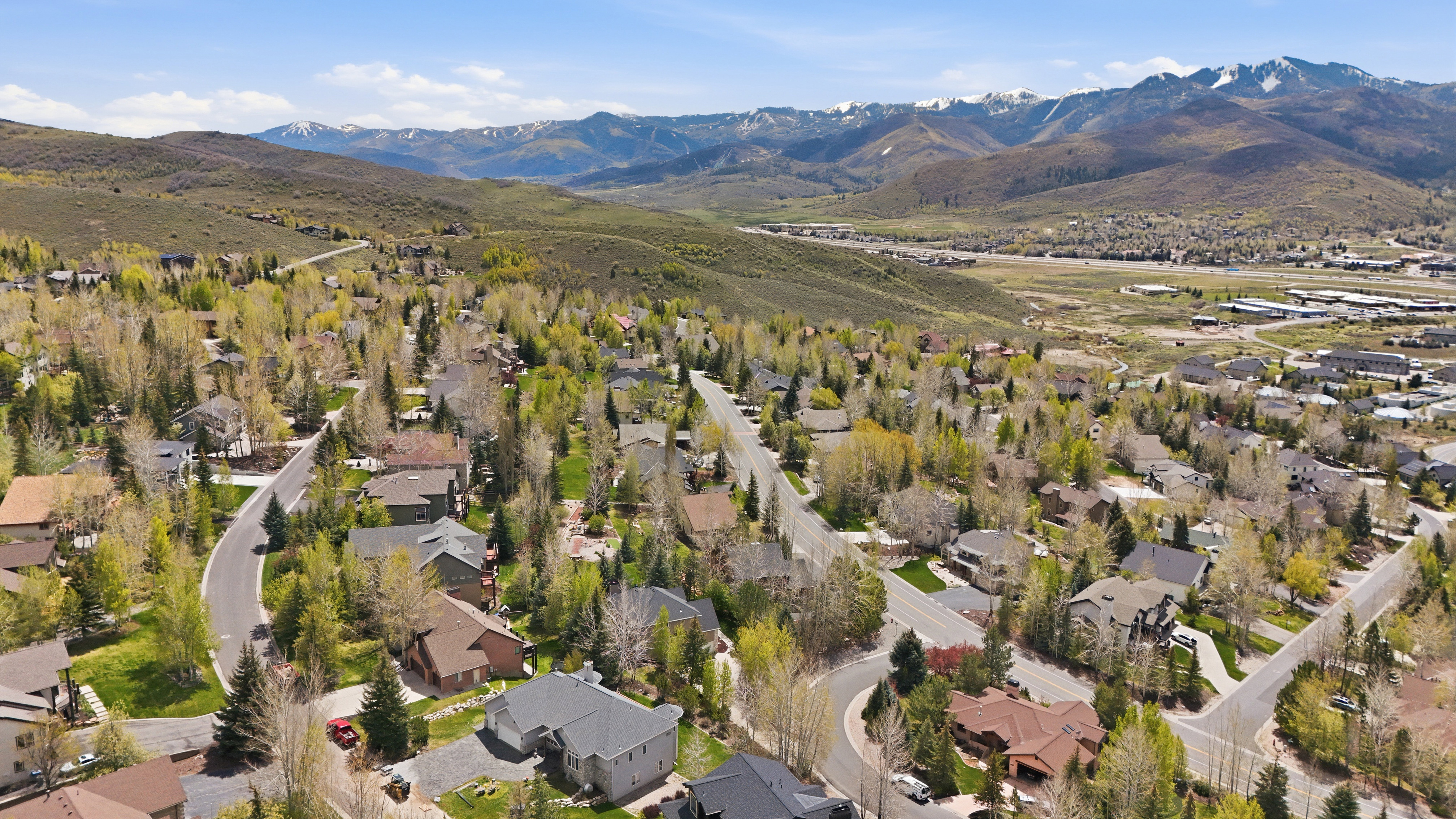 Residential community featuring mature trees and paved roadways, set against a backdrop of distant mountains