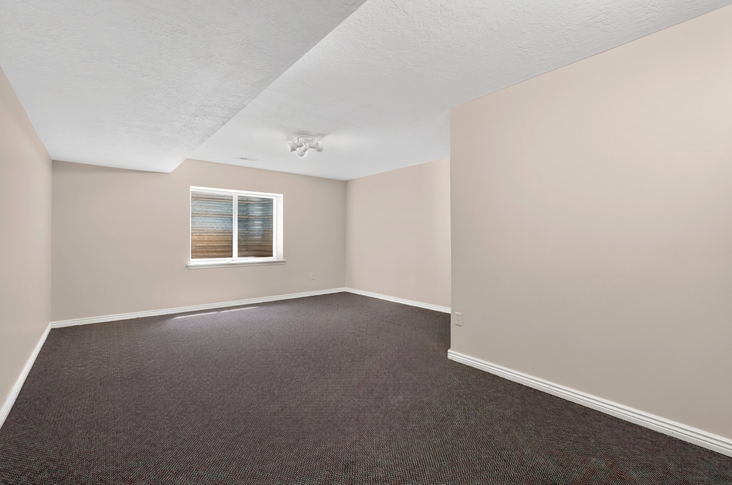 Carpeted room featuring neutral wall paint, white baseboards, and a window with white trim