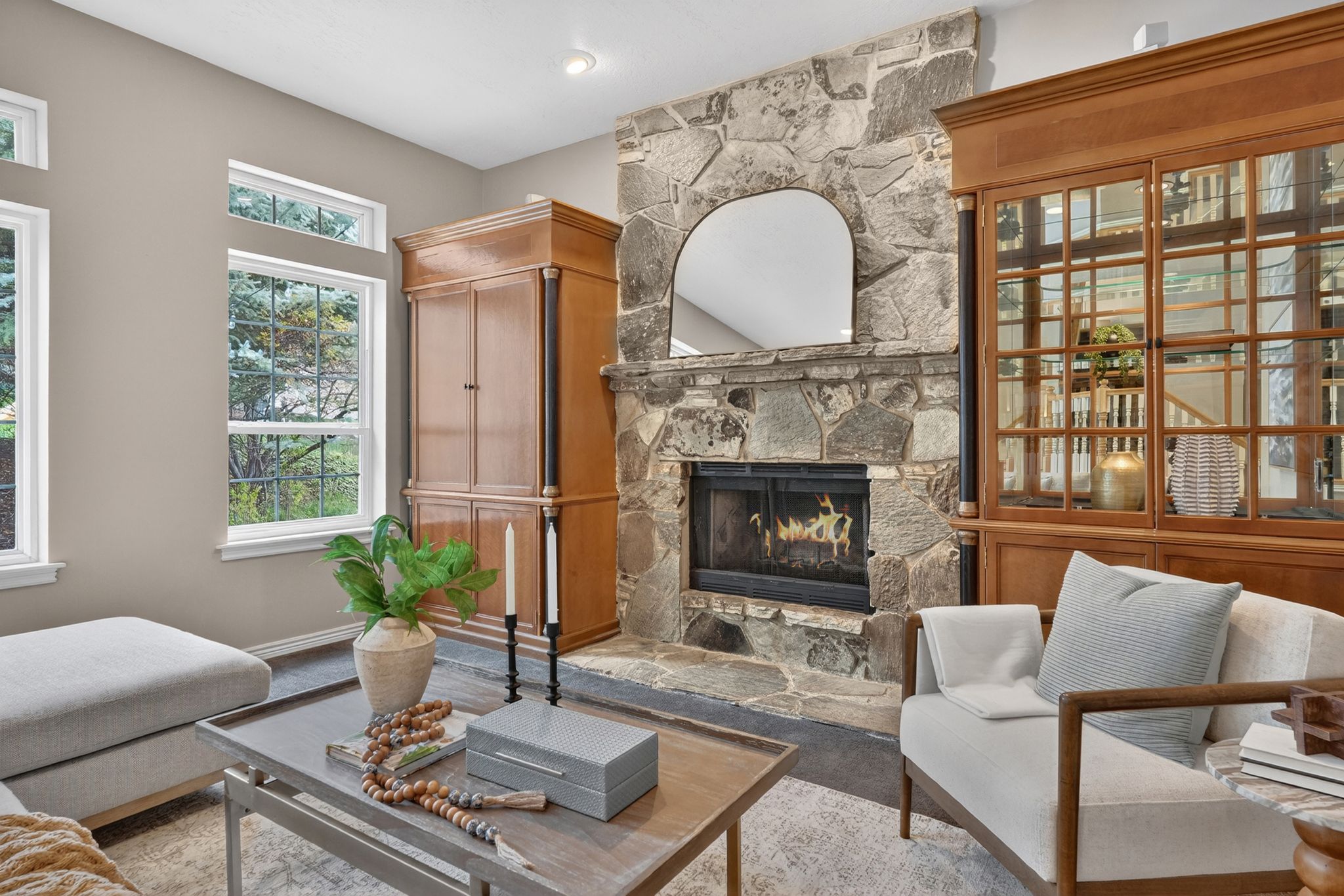 Natural stone fireplace with hearth, recessed lighting, and multiple windows